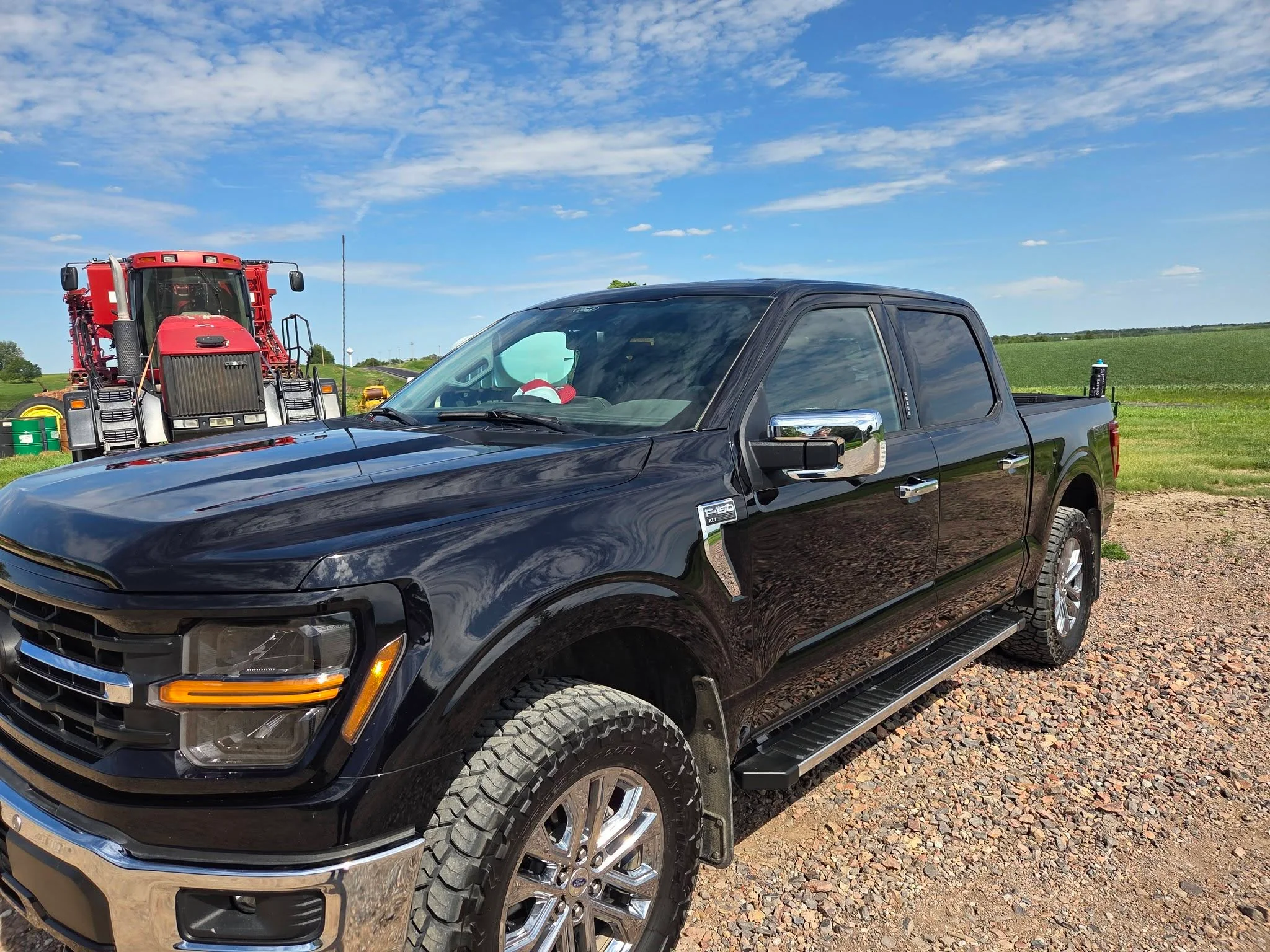 Black Ford F-150 detailed, parked by a tractor in a Thayer County field